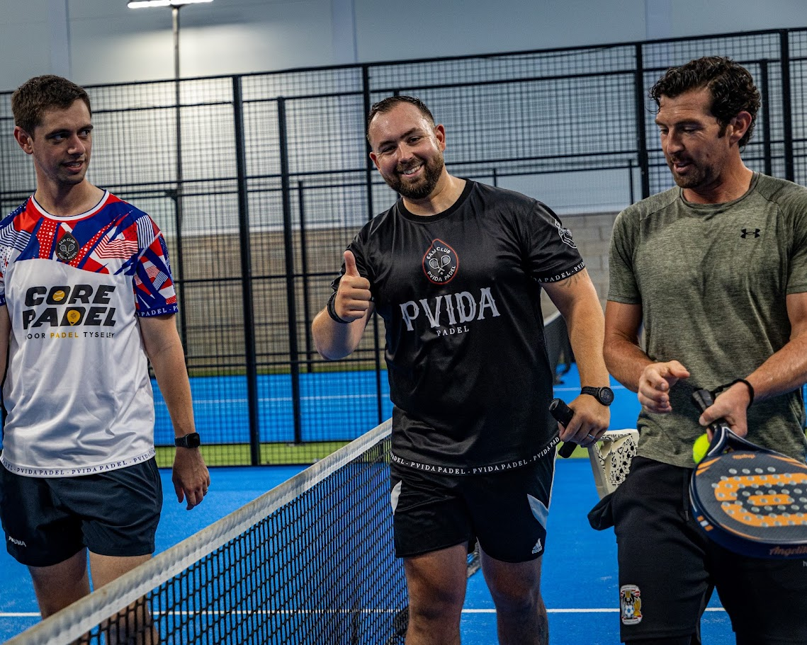 Three players sharing a laugh at the net between matches