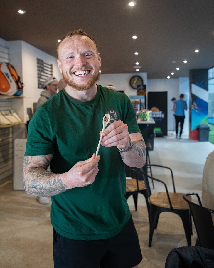 A player grinning as he collects the wooden spoon at the presentation